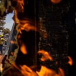 Aggressive Suppression: Emergency response crews and multi-agency air tankers battle the fast-growing Sandy Fire in image_25.png. The brush fire ignited just after 10:00 a.m. near Sandy Avenue in Simi Valley, reportedly sparked accidentally when a tractor struck a rock. Whipped by shifting winds, the flames quickly scorched 1,364 acres with 0% containment by late Monday night, forcing the mandatory evacuation of more than 10,000 homes. Governor Gavin Newsom successfully secured a Federal Emergency Management Agency (FEMA) grant to help fund the massive mobilization of over 750 firefighters on the front lines. Photo: Lance Orozco / KCLU News via Associated Press