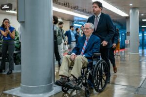 former Senate Republican Leader Mitch McConnell is assisted by an aide while using a wheelchair in the hallways of the U.S. Capitol complex. McConnell began regularly utilizing a wheelchair to navigate the Capitol following a series of health challenges and falls. Source: Getty Images North America / Congressional Pool Archive