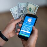 A smartphone displaying the official *my Social Security* login portal alongside U.S. dollar banknotes. **Photo:** Stock photo via Getty Images / Shutterstock