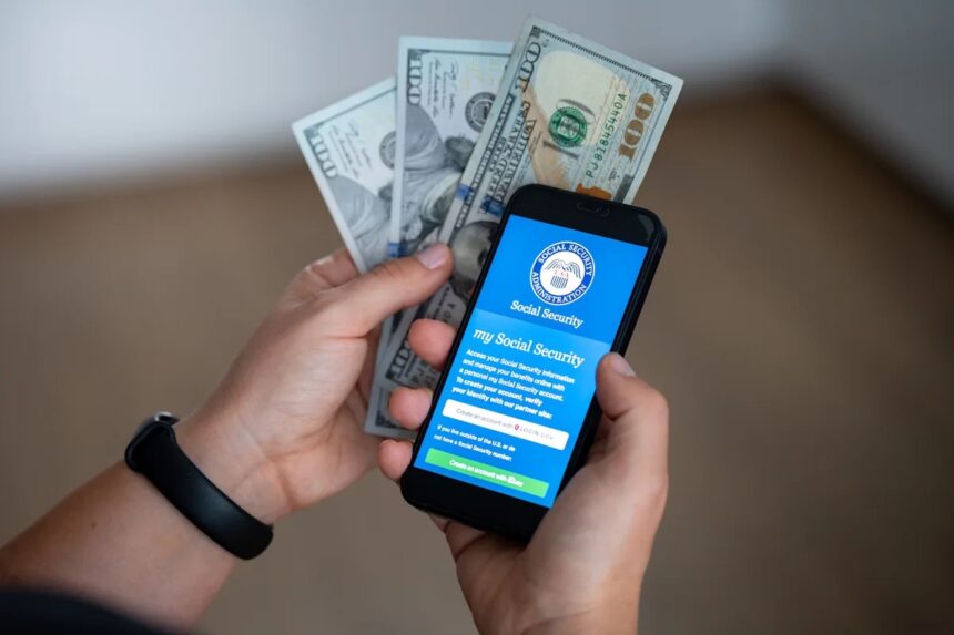 A smartphone displaying the official *my Social Security* login portal alongside U.S. dollar banknotes. **Photo:** Stock photo via Getty Images / Shutterstock